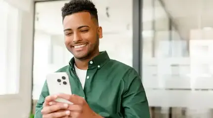 A man in a green shirt using his cell phone to access Winchester's Online Banking.
