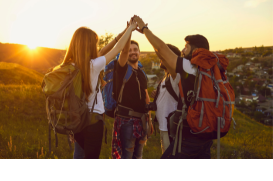 a group of backpackers holding hands in front of a sunset