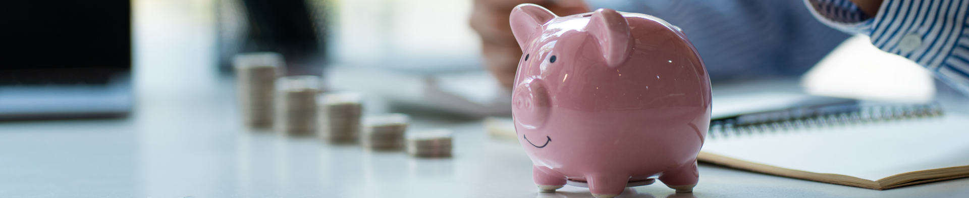Businessman placing coins into a piggy bank, symbolizing saving, financial planning, and growth.