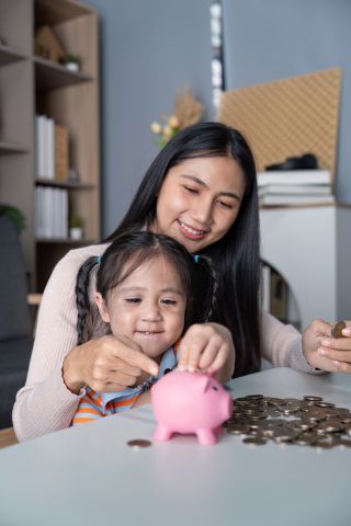 Mom and daughter putting change in piggy bank