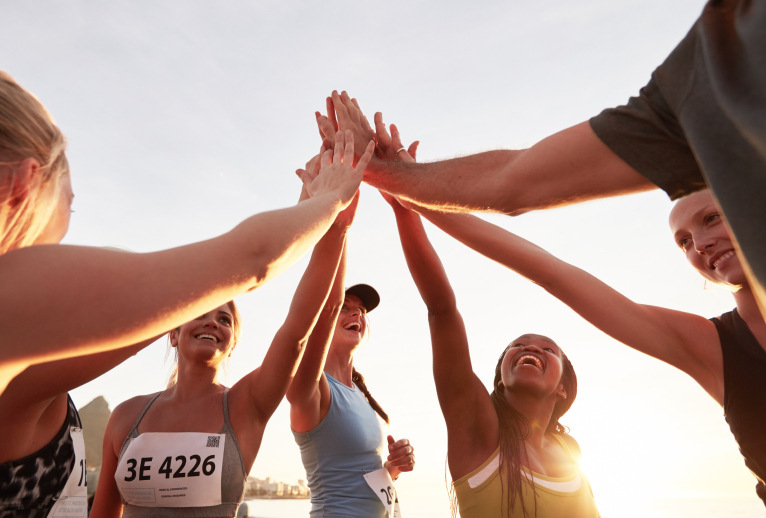 Marathon runners all high fiving at the end of the marathon.